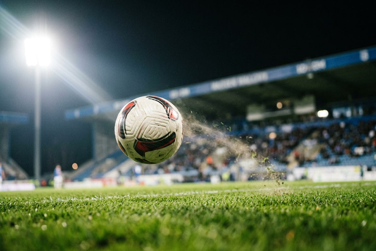 Close-up action shot of a soccer ball in flight over a illuminated stadium pitch.
